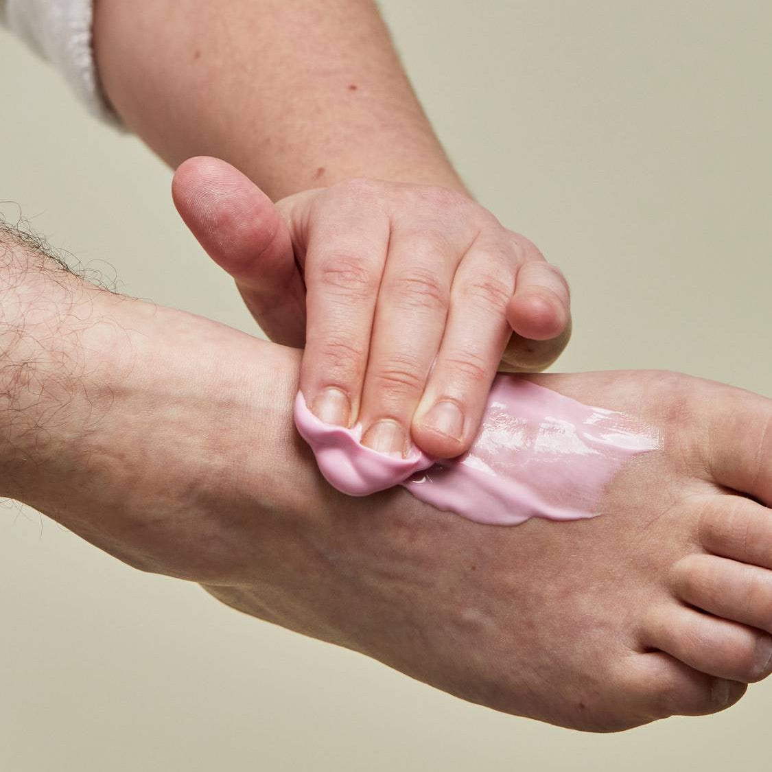 A person applying lotion on his foot