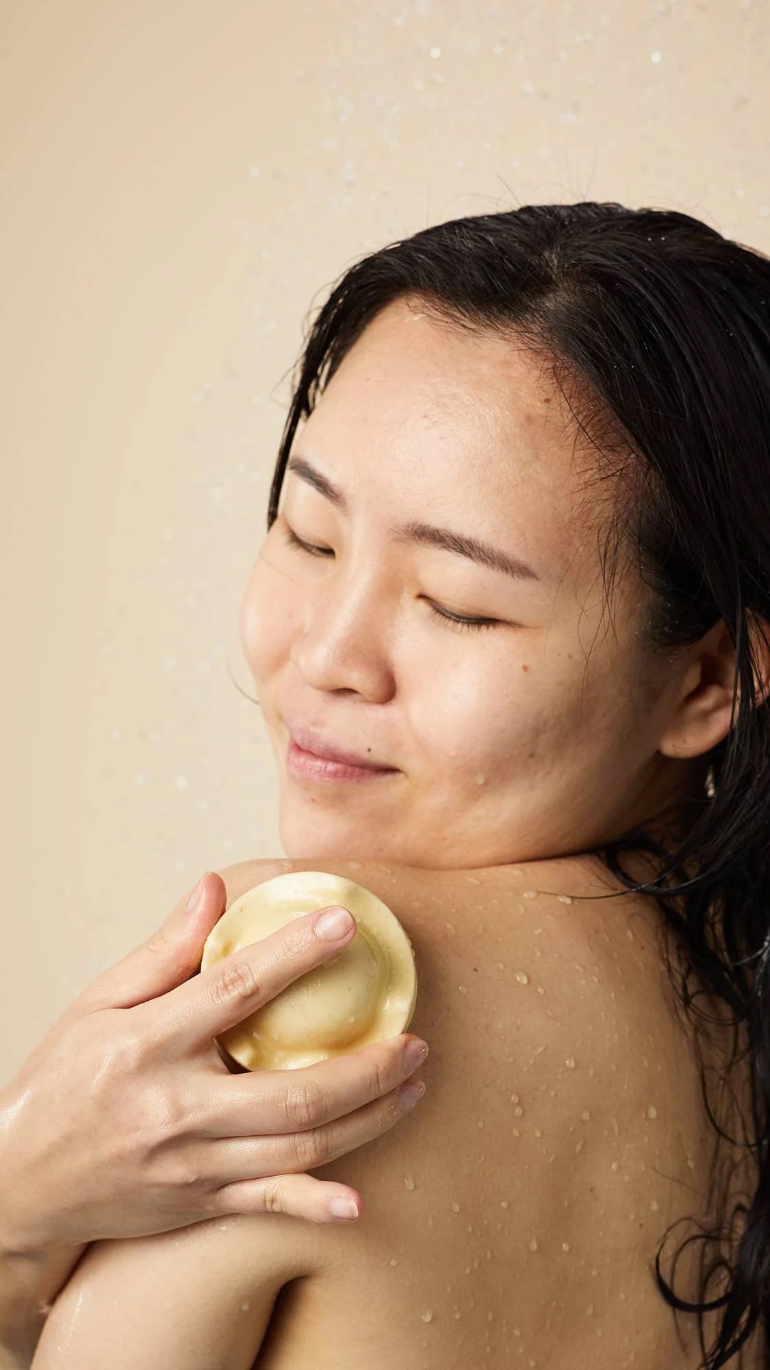 Person enjoying the Lush Beirut King of Skin solid body butter, gliding it on their shoulder for soft, nourished skin, enriched with oat milk and banana.
