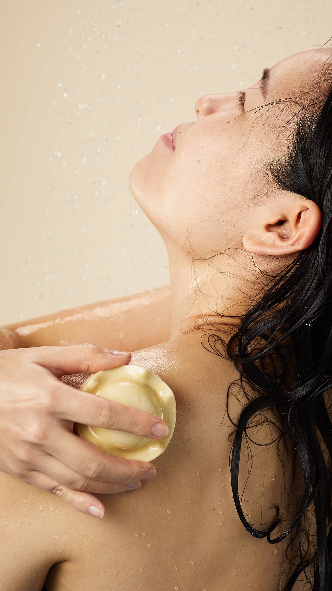 Person applying Lush Beirut King of Skin solid body butter on their shoulder, enjoying a hydrating experience with nourishing oat milk and banana.