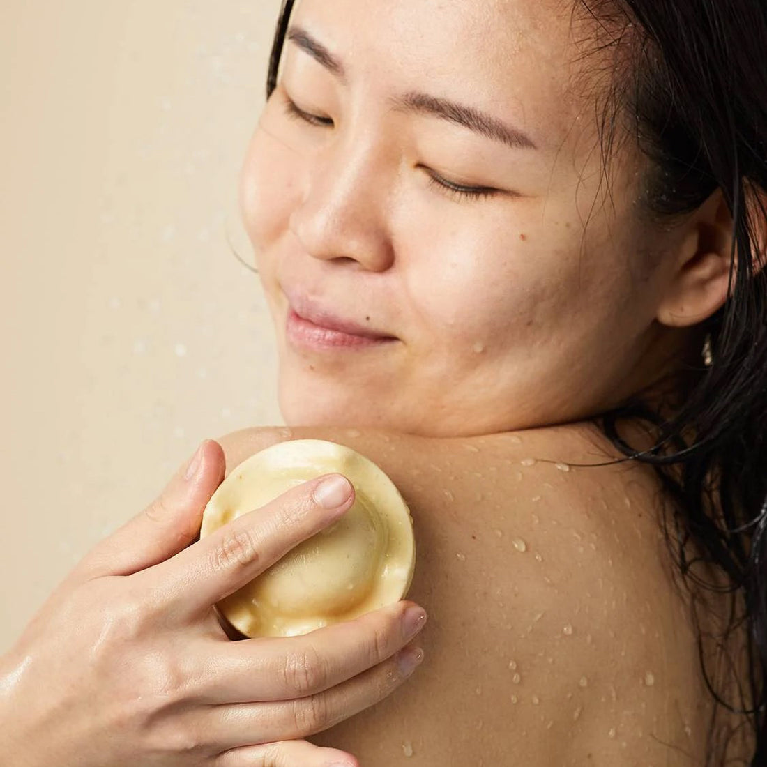 Person enjoying the Lush Beirut King of Skin solid body butter, gliding it on their shoulder for soft, nourished skin, enriched with oat milk and banana.