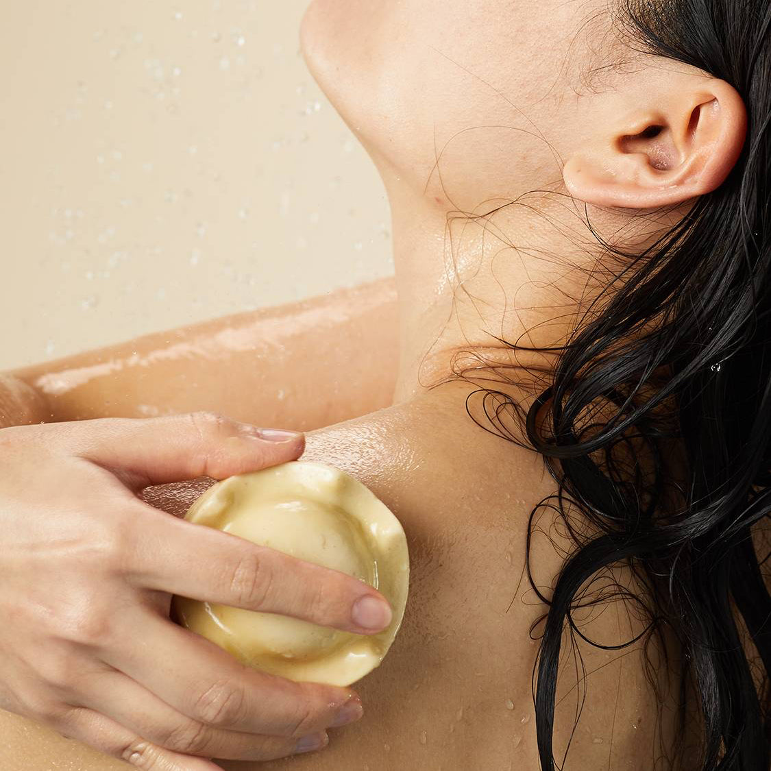 Person applying Lush Beirut King of Skin solid body butter on their shoulder, enjoying a hydrating experience with nourishing oat milk and banana.