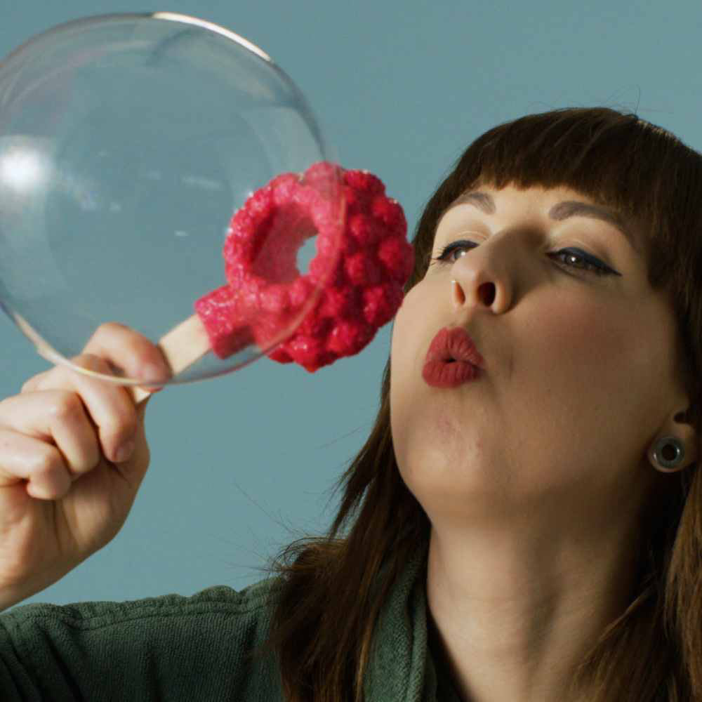Woman blowing a bubble using Lush&