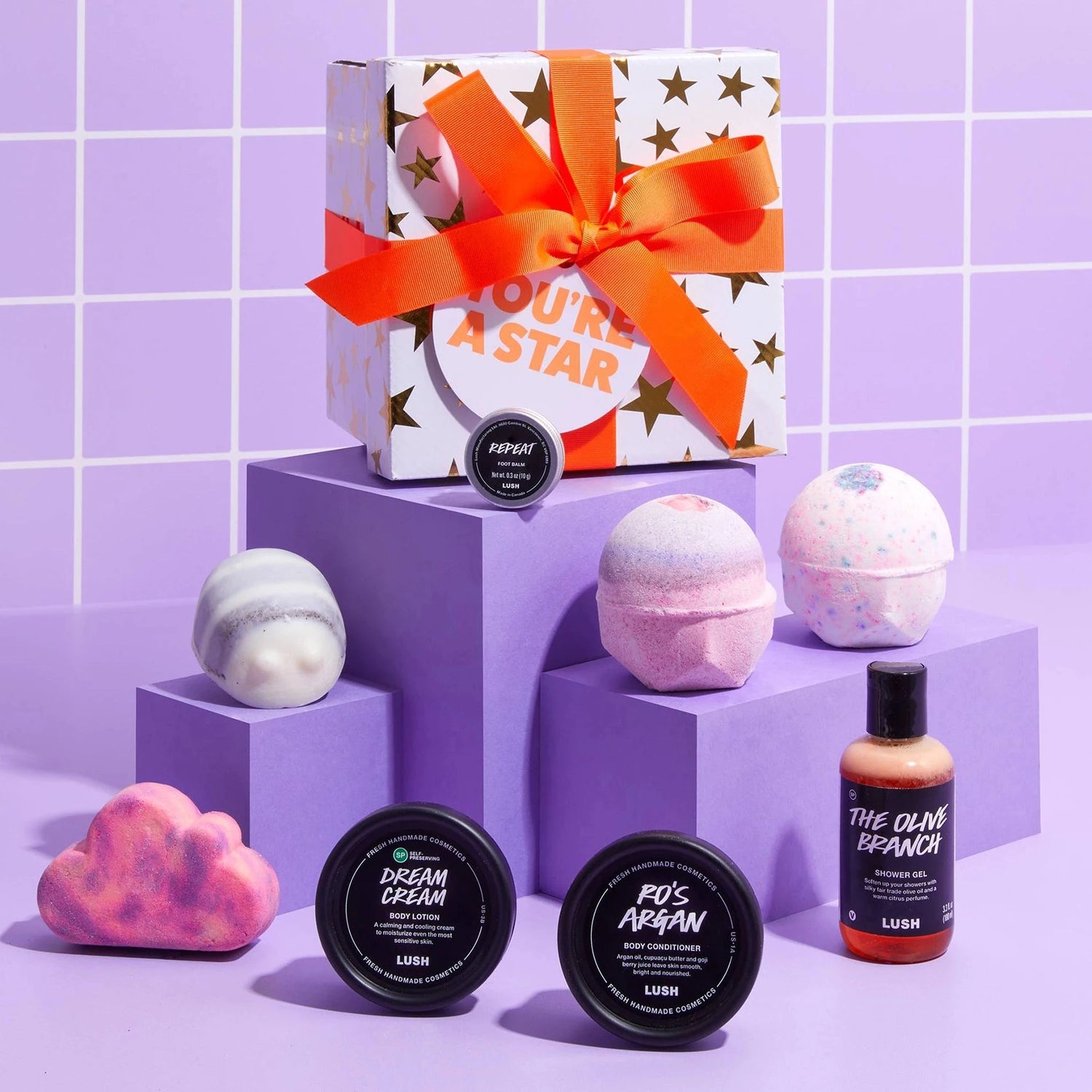 Bath products including bath bombs and soaps on a purple tiled background