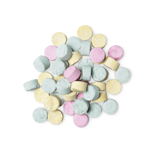 A pile of small, circular, multicoloured Refresher toothpaste tabs shot from above.