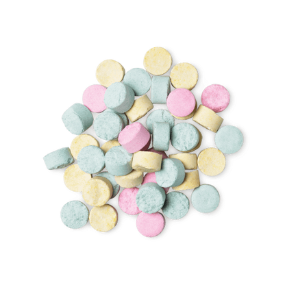 A pile of small, circular, multicoloured Refresher toothpaste tabs shot from above.