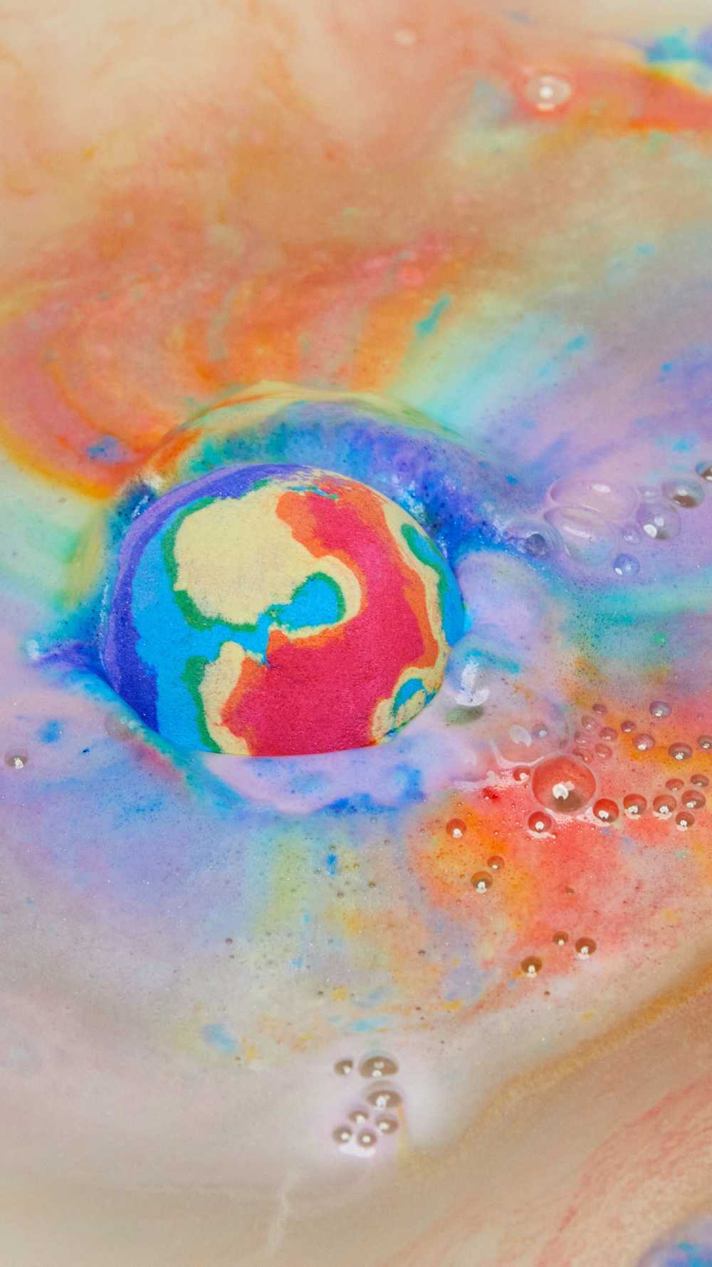 The thermal Waves bath bomb is dissolving leaving behind a thick, velvety blanket of bright rainbow swirls across the surface of the water.