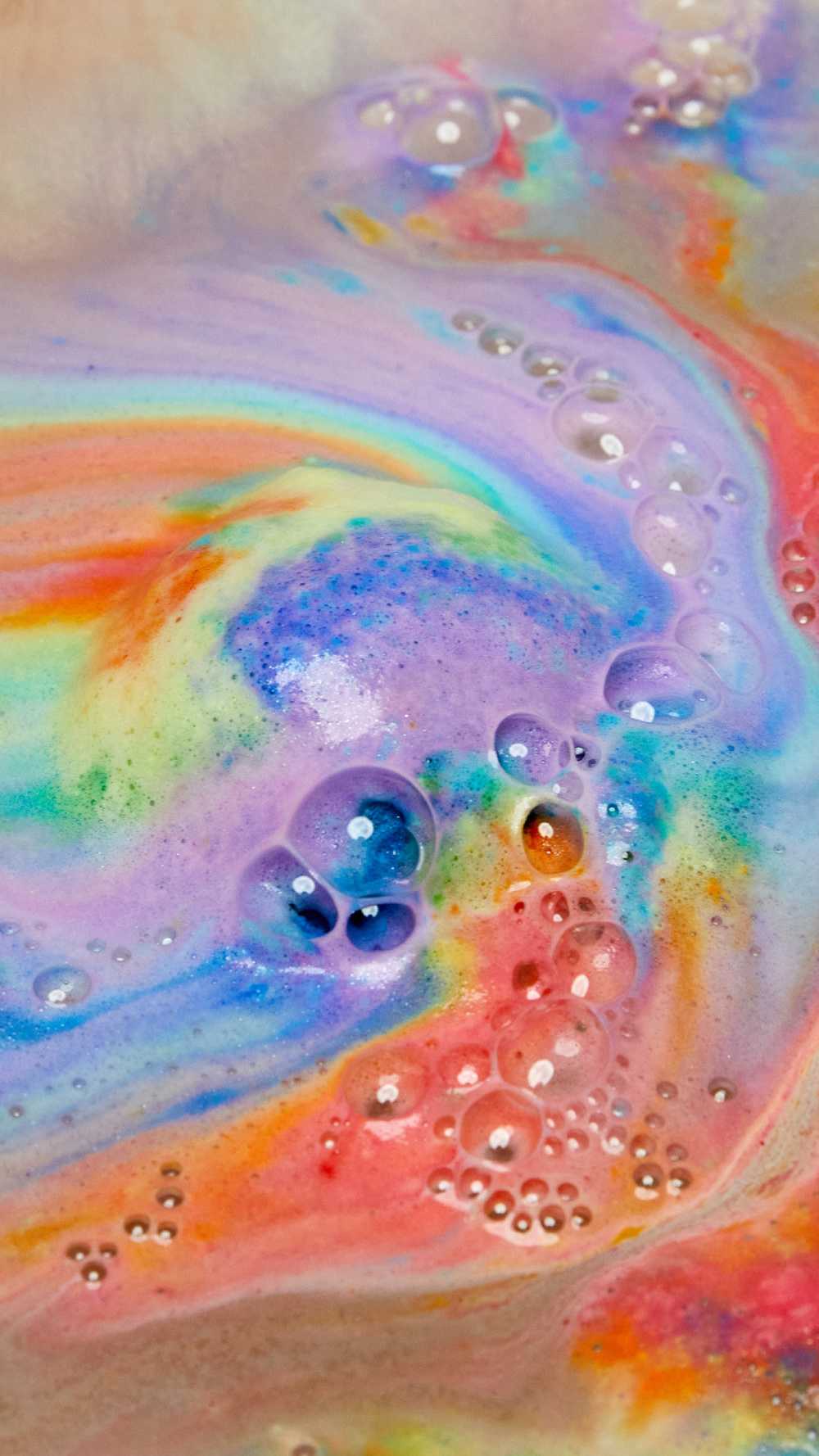 The thermal Waves bath bomb is dissolving leaving behind a thick, velvety blanket of bright rainbow swirls across the surface of the water.
