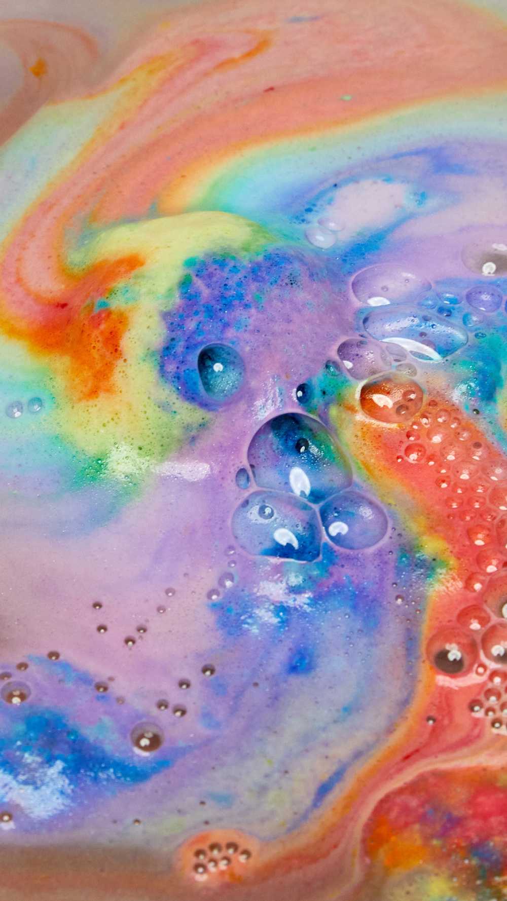 The thermal Waves bath bomb is dissolving leaving behind a thick, velvety blanket of bright rainbow swirls across the surface of the water.