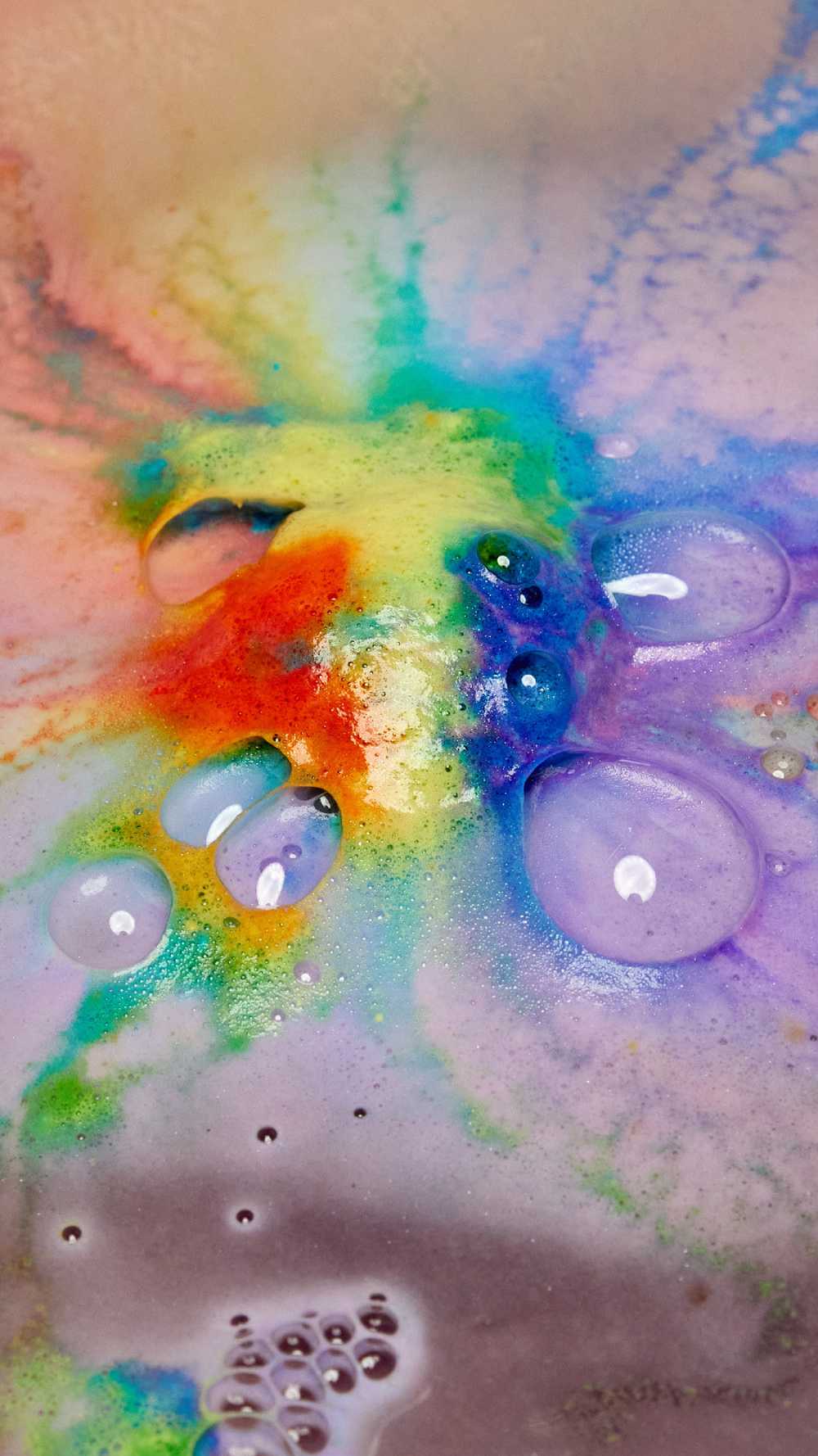 The thermal Waves bath bomb is dissolving leaving behind a thick, velvety blanket of bright rainbow swirls across the surface of the water.