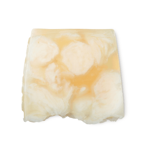 Bohemian. A light yellow, creamy swirled, smooth, trapezium shaped soap, with bumps along its left side.